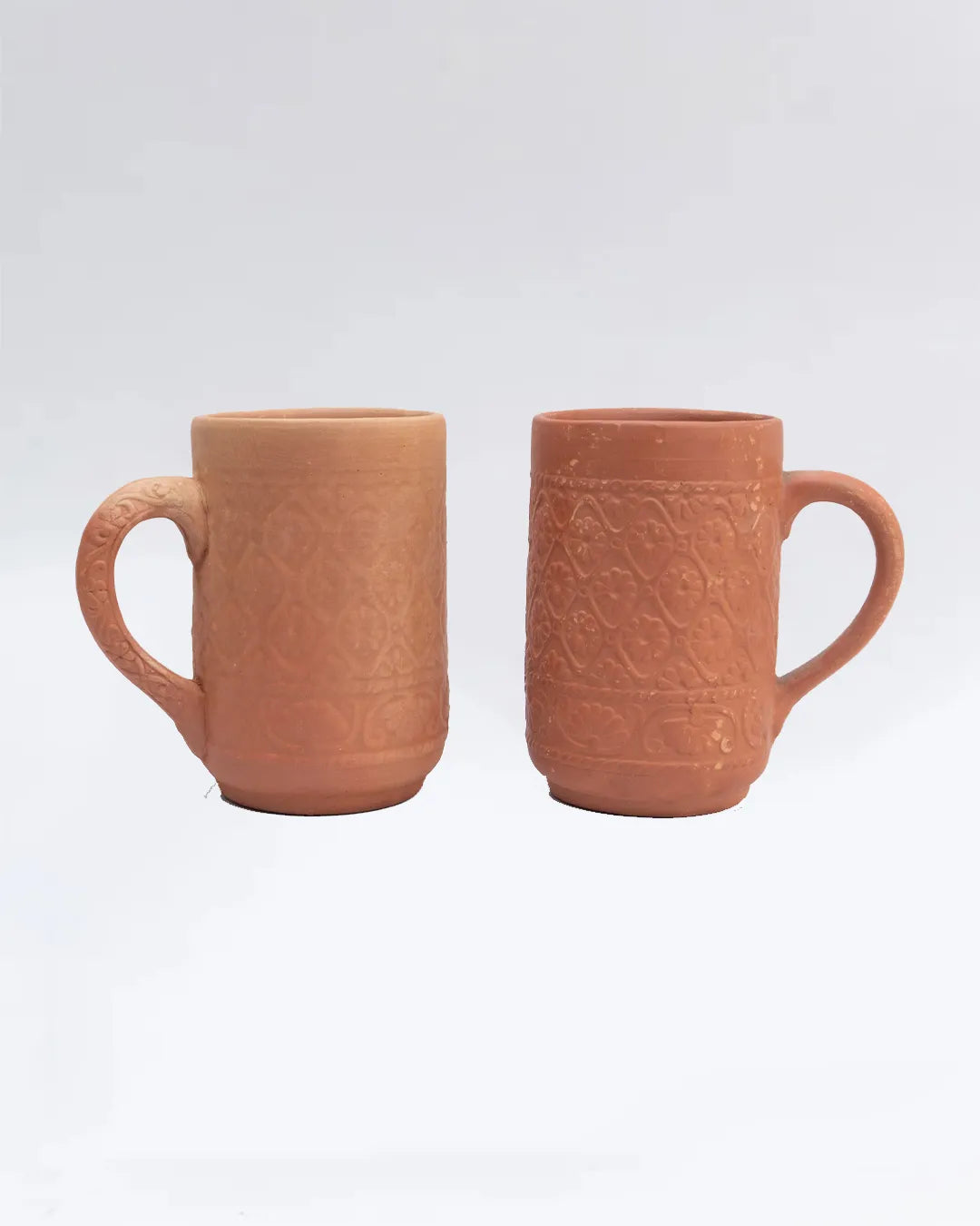 Two terracotta mugs with textured design on a white background