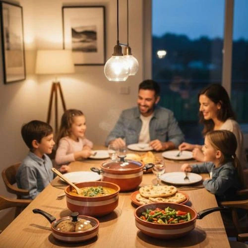 Family of four sitting around a dinner table with various dishes, smiling and enjoying their meal.